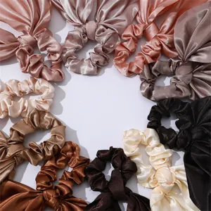 Set of satin hair scrunchies with long ribbon bows in neutral earthy tones for women.
