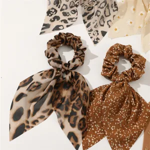 Close-up view of elegant leopard print and daisy floral ribbon hair scrunchies detail.