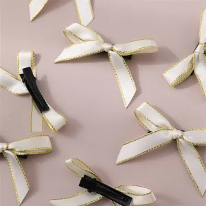 White ribbon bow hair clips with gold trim, sweet style women's hair accessory detail.