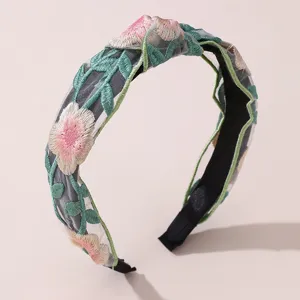 Detailed view of wide embroidered floral headband with mesh fabric and pink flowers, elegant.
