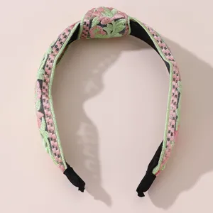Embroidered knot headband detail showing pink and green floral stitching and wide band design.