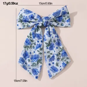 Blue floral chiffon bow hair clip detail view, featuring delicate rose print and elegant drapes.