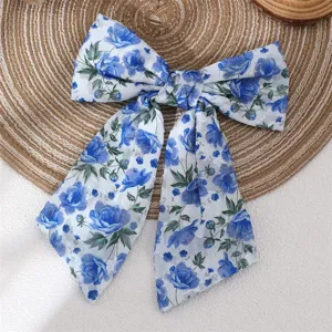 Close-up detail of elegant blue floral chiffon bow hair clip showing soft fabric texture.
