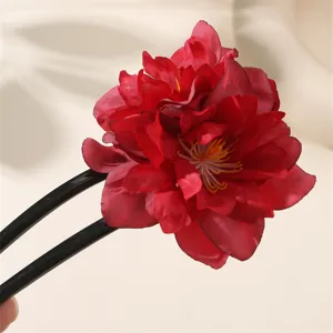 Primo piano della forcina per capelli a U con fiore in tessuto rosso dal design minimalista.