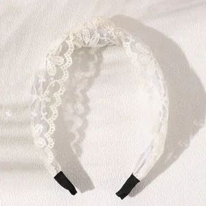 Close-up detail of the elegant beige lace knot headband, showing fine floral fabric texture.