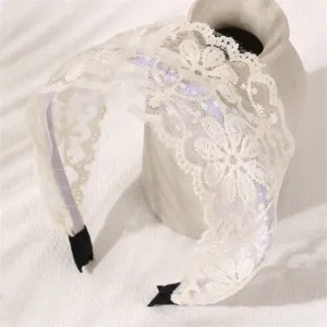 Detailed close-up of elegant white lace wide hair hoop, delicate floral pattern design.