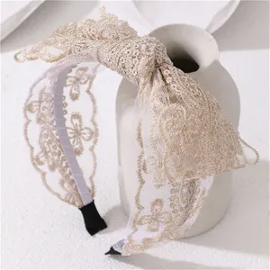 Detailed close-up of the elegant gold lace bow headband with delicate floral embroidery design.