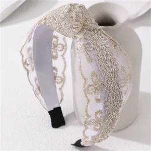 Detailed shot of elegant wide lace headband with delicate floral embroidery and knot design.