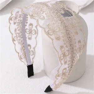 Close-up detail of wide lace headband with golden embroidery and elegant wavy edge design.