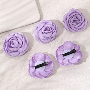 Purple fabric rose hair clip detail showing texture and alligator clip backing clearly.