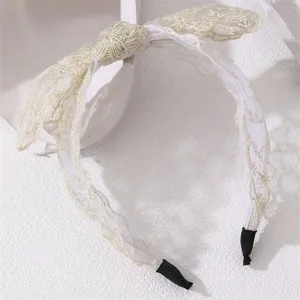Delicate gold wire embroidered mesh bow headband detail close-up showing fine texture.