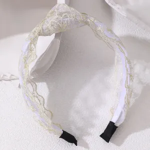 White lace knotted headband detail featuring fine gold embroidery and black tips.
