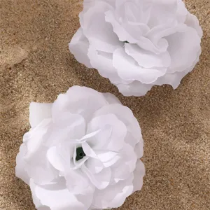 Détail de fleur en tissu blanc, gros plan d'accessoire rose artificielle sur fond de sable.