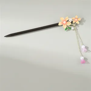 Close-up of traditional Chinese hair hairpin with orange floral enamel, pearls, and tassels.