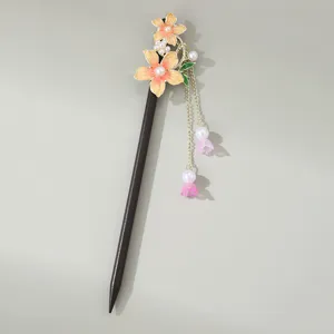 Detail of traditional chinese hair stick with orange enamel flowers and hanging pearl tassels.