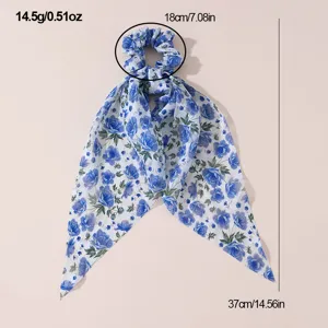 Blue floral chiffon hair scrunchie with long ribbon bow, elegant hair accessory detail view.