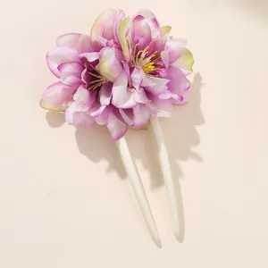 Primo piano di un fermaglio per capelli a U floreale con fiori rosa e bastoncino bianco.