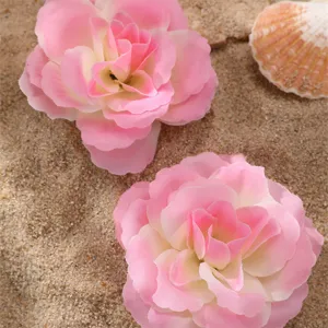 Gros plan détail de l'accessoire de cheveux fleur artificielle rose dégradé sur le sable.