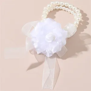 Dettaglio del corsetto da polso da sposa bianco con perle finte e nastro floreale delicato.