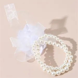 Primo piano del fiore da polso da sposa bianco con perle a doppio strato e fiocco in tessuto.
