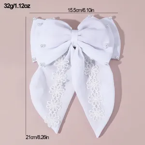 Detailed view of the white fabric hair bow featuring delicate lace flower trim and pearls.