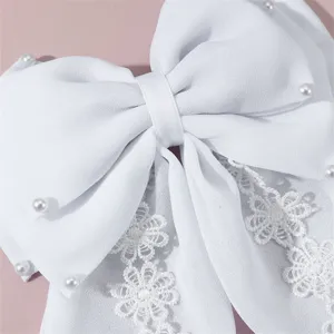 Closeup view of the elegant white fabric hair bow with delicate pearls and lace details.