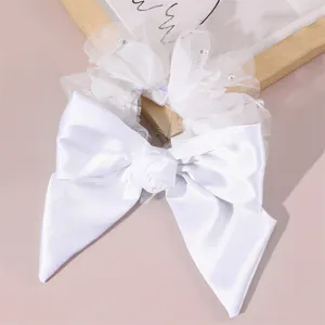 White satin bow hair scrunchie featuring elegant mesh and pearls for bridal wedding hairstyles.