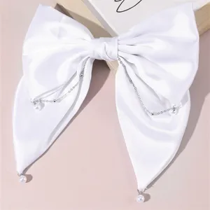 Elegant white satin bow hair clip with delicate pearl and chain drapes for bridal and daily wear.