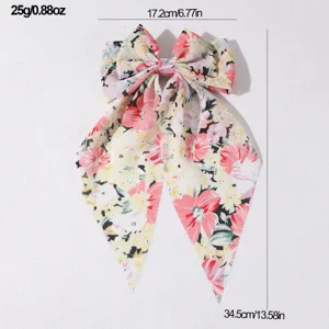 Detailed view of the floral fabric hair bow, showing its elegant ribbon tails and vibrant print.