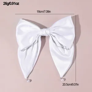 White satin bow hair clip with pearl chain details, elegant bridal hair accessory for weddings.