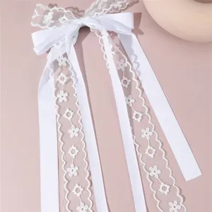 White fabric bow hair accessory with lace long ribbons elegant bridal hair clip detail view.