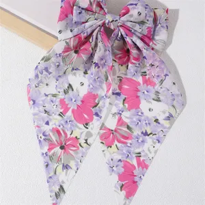 Close-up detail of a sweet floral fabric hair bow with long ribbons and elegant style.