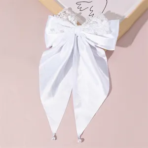 Elegant white satin bow hair clip with delicate lace and hanging pearls for bridal styling.