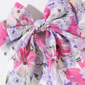 Detailed shot of a sweet floral fabric hair bow with long ribbons, elegant spring hair clip.