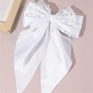 Elegant white satin hair bow with delicate lace overlay and pearl details for bridal events.