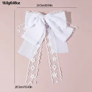 White fabric lace bow hair clip with long ribbons and pearl detail, elegant bridal accessory.