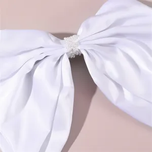 White satin hair bow clip detail with delicate pearl center for bridal wedding hair accessories.