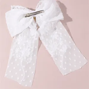 Detailed view of white lace bow hair clip featuring delicate streamers and a secure metal clip.