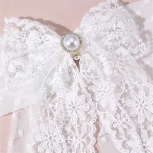 White lace hair bow detail close-up, featuring elegant pearls and sparkling rhinestone center.