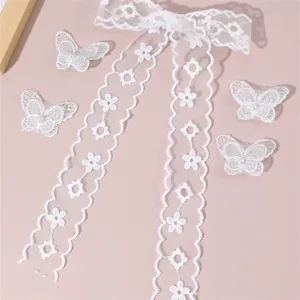 Detailed view of white lace bow hair ribbon and butterfly clips with faux pearls, delicate embroidery.