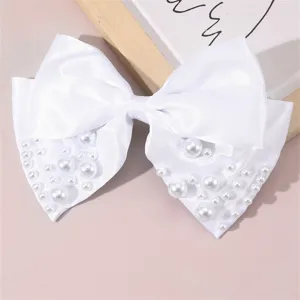 Detailed close-up of a white satin bow hair clip adorned with elegant faux pearls.