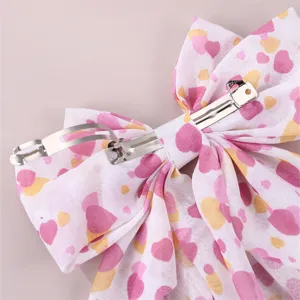 Detail view of pink heart fabric bow hair clip back metal spring barrette mechanism.