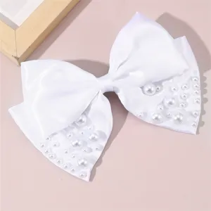 White satin bow hair clip detail shot with faux pearls, elegant bridal hair accessory.