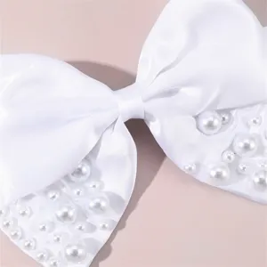 Details of the elegant white satin bow hair clip adorned with glossy pearls for weddings.