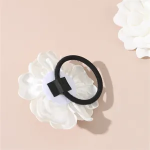 White fabric flower hair tie detail showing elastic band and backing for bridal wedding hairstyles.