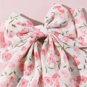 Close-up detail of pink floral fabric hair bow clip with long ribbons, sweet sweet style.