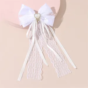 White lace bow hair clip detail shot featuring long streamers and sweet pearl heart accent.