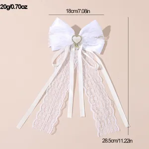 White fabric bow hair clip with delicate lace and pearl pendant, elegant bridal accessory.