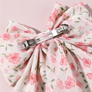 Close-up detail of a sweet pink floral print fabric bow hair clip with metal spring clip back.