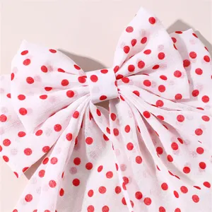 Detail of sweet red polka dot hair bow clip, elegant fabric bow with long ribbon for women.